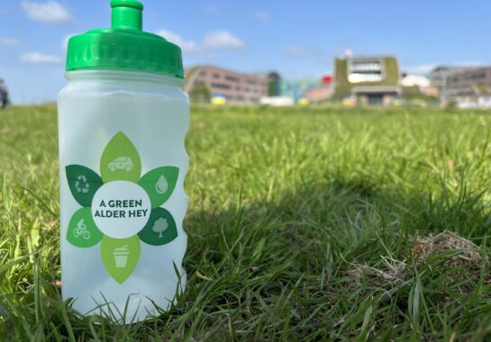 A water bottle sitting on grass with Alder Hey in background