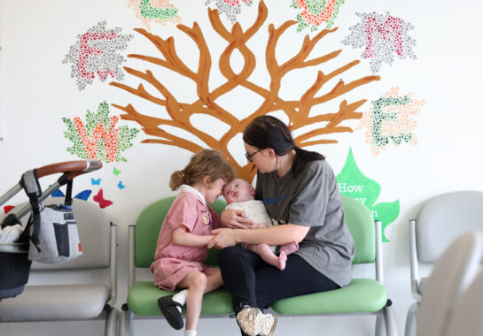 Parent holding baby with sibling next to them