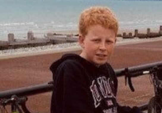 Harry posing for a picture with a beach and the sea in the background