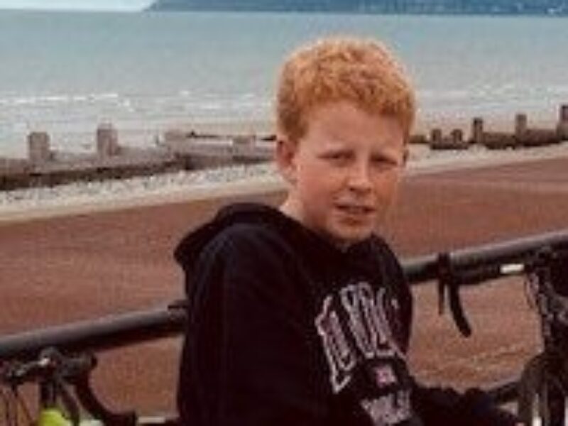 Harry posing for a picture with a beach and the sea in the background